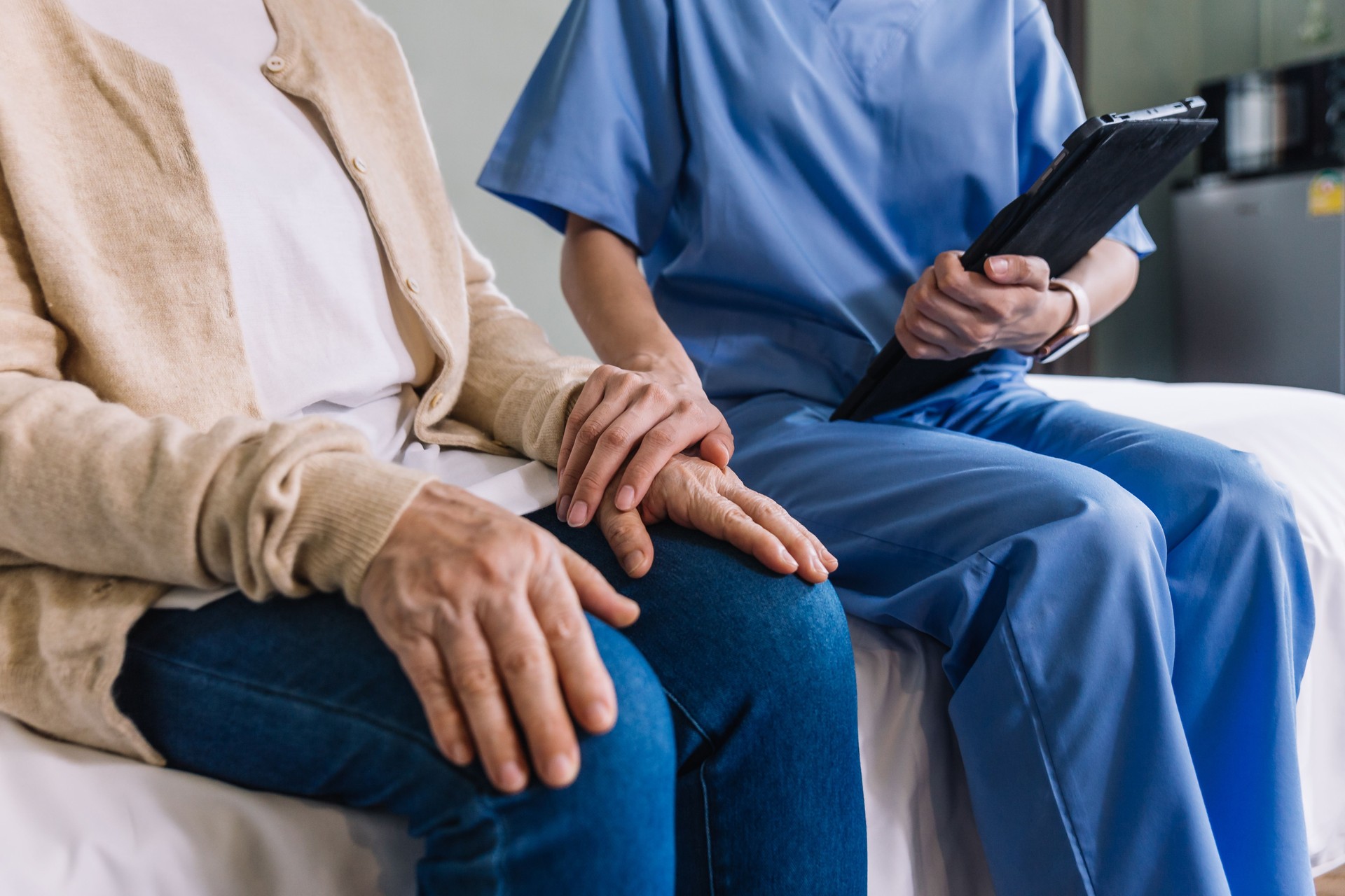 Mano della donna asiatica senior in primo piano con il suo caregiver che aiuta le mani, visita del caregiver a casa. Concetto di assistenza sanitaria domiciliare e casa di cura.